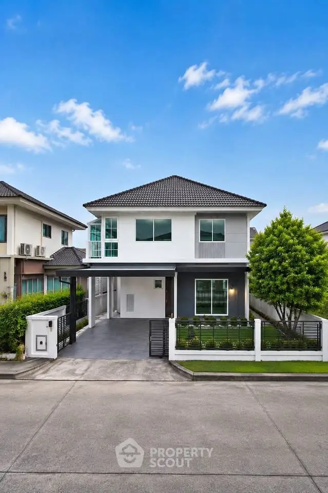 Modern two-story house with sleek design and spacious driveway in a suburban neighborhood.