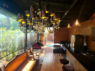 Luxurious living room with elegant chandelier and rustic brick walls, featuring stylish seating and natural light.
