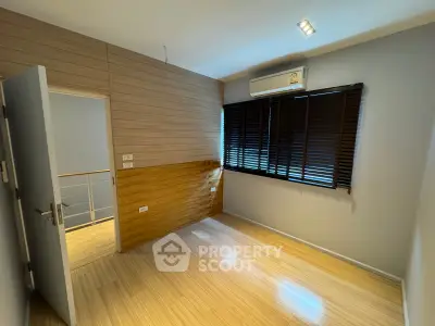Modern bedroom with wooden flooring and air conditioning in a stylish home.