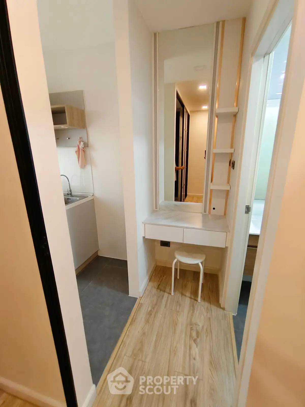 Modern apartment hallway with wooden flooring and compact kitchen area