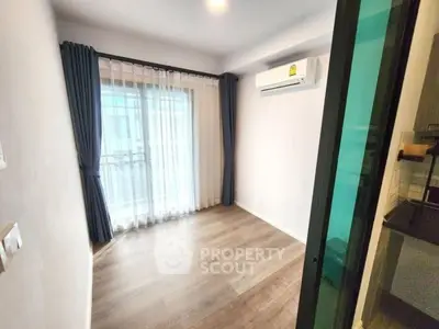 Bright empty room with wooden flooring and large window, ideal for customization.