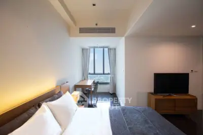 Modern bedroom with ocean view, featuring sleek furniture and large window for natural light.