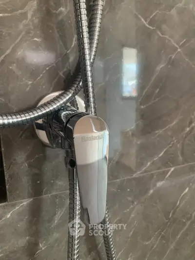 Modern bathroom shower fixture with sleek chrome finish on marble wall.