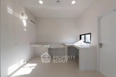 Modern minimalist kitchen with sleek white countertops and ample natural light