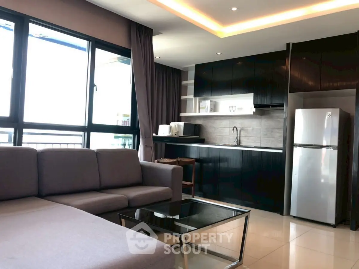 Modern living room with sleek kitchen, large windows, and stylish furniture in a contemporary apartment.