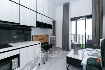Modern living room with sleek kitchen and balcony view in a stylish apartment.
