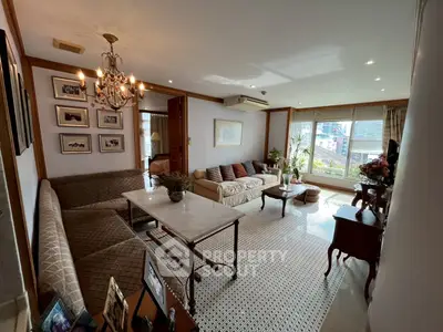 Elegant living room with chandelier, cozy seating, and large windows offering natural light.