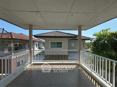 Spacious balcony with modern railing and scenic view of neighboring houses and lush greenery.