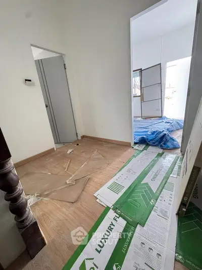 Spacious interior under renovation with modern flooring and ample natural light.