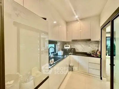 Modern kitchen with sleek white cabinets and marble backsplash in a contemporary apartment.