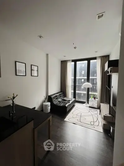 Modern living room with sleek black sofa and floor-to-ceiling windows in urban apartment