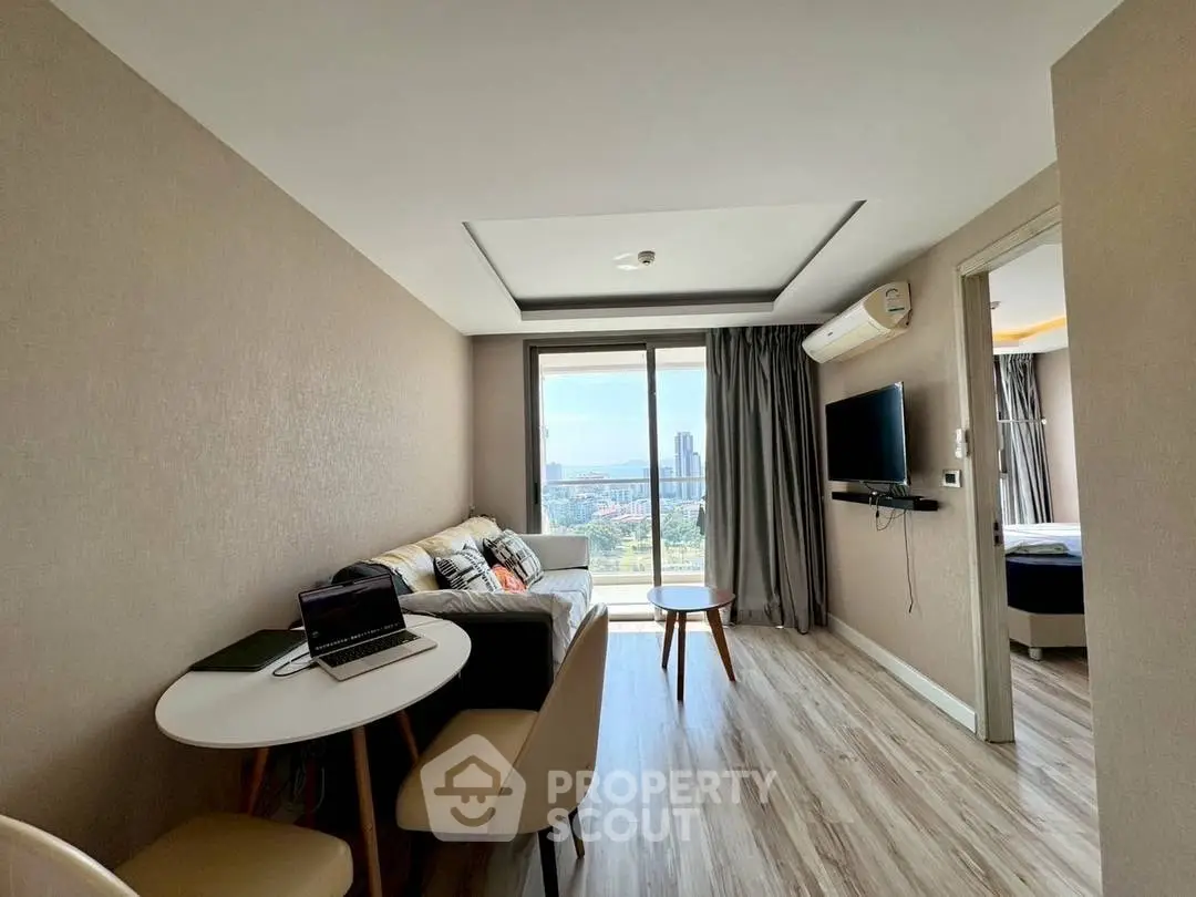 Modern living room with city view, featuring cozy seating and a wall-mounted TV.