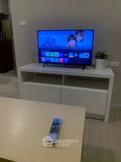 Modern living room with TV and sleek white furniture, perfect for cozy entertainment nights.