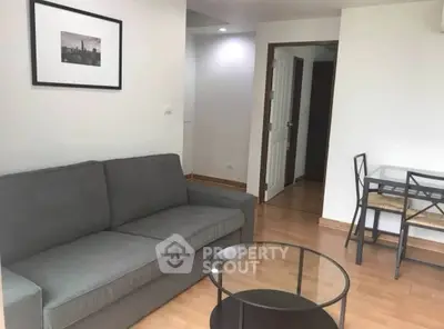 Cozy living room with modern gray sofa and glass coffee table in a stylish apartment.