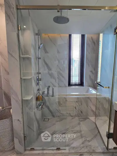 Luxurious marble bathroom with glass shower and bathtub, perfect for relaxation.