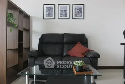 Elegant living room with a plush black leather sofa, glass coffee table, and chic wall art, perfect for modern urban living.