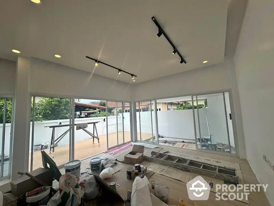 Spacious under-construction living room with large windows and sliding doors opening to a big balcony.