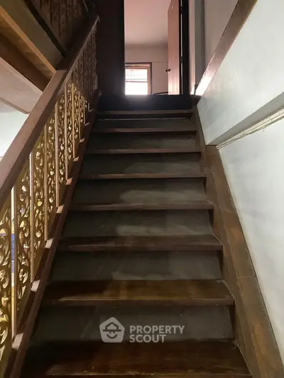 Charming wooden staircase with ornate railing leading to upper floor