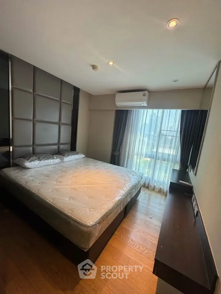 Modern bedroom with large window and stylish decor in a high-rise apartment.