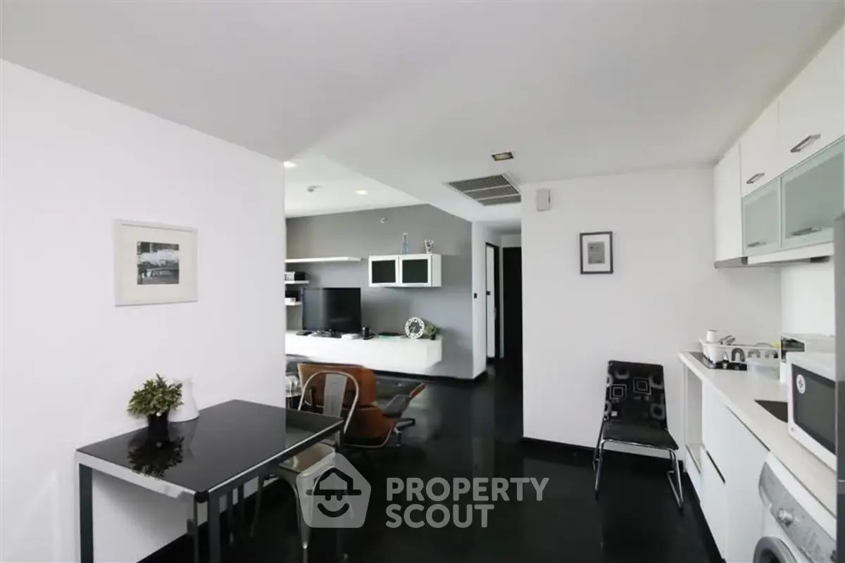 Modern open-plan living room and kitchen with sleek black and white decor, perfect for urban living.