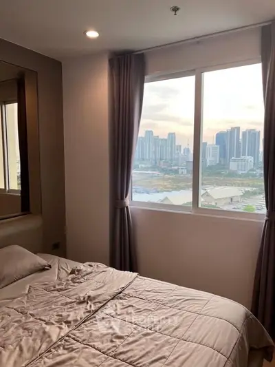 Cozy bedroom with city view, featuring a large window and elegant curtains, perfect for urban living.