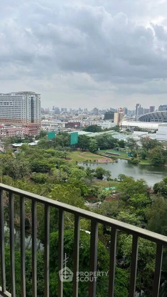 Stunning cityscape view from a high-rise balcony overlooking lush greenery and urban skyline.