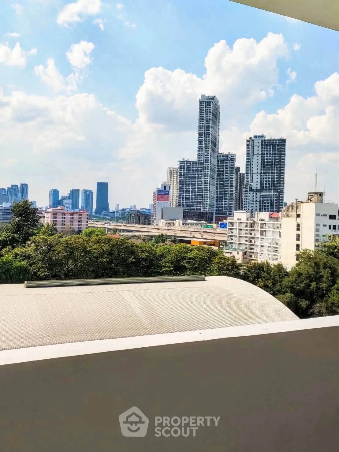Stunning cityscape view from a modern balcony overlooking skyscrapers and lush greenery.