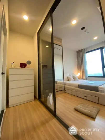 Modern bedroom with sliding glass wardrobe and wooden flooring