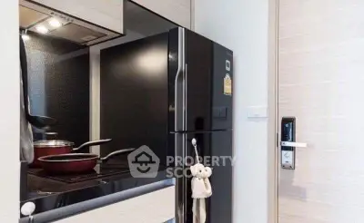Modern kitchen with sleek black fridge and induction cooktop in a stylish apartment.
