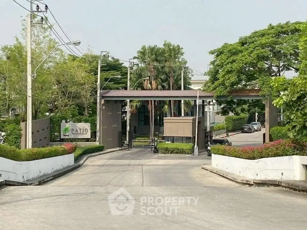 Gated community entrance with lush greenery and modern design, perfect for serene living.