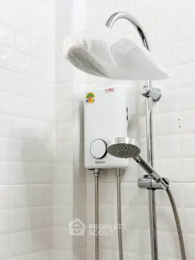 Modern bathroom with sleek showerhead and water heater, featuring white tiled walls.