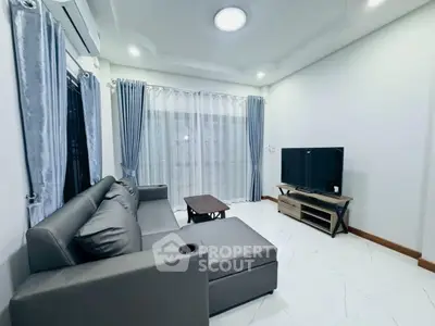 Modern living room with sleek gray sofa and large TV, featuring elegant curtains and bright lighting.