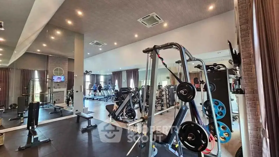 Spacious modern gym with state-of-the-art equipment and large mirrors in luxury real estate.
