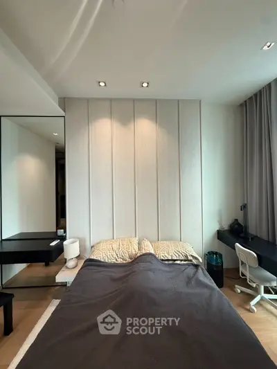 Modern bedroom with stylish decor and workspace, featuring a cozy bed and sleek desk setup.