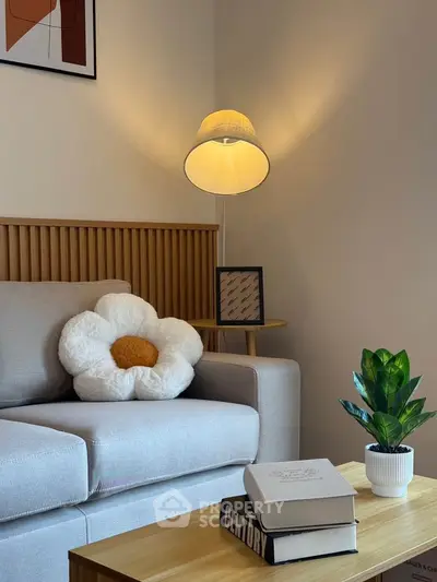 Cozy living room with stylish decor, featuring a plush sofa, unique flower pillow, and modern lamp.