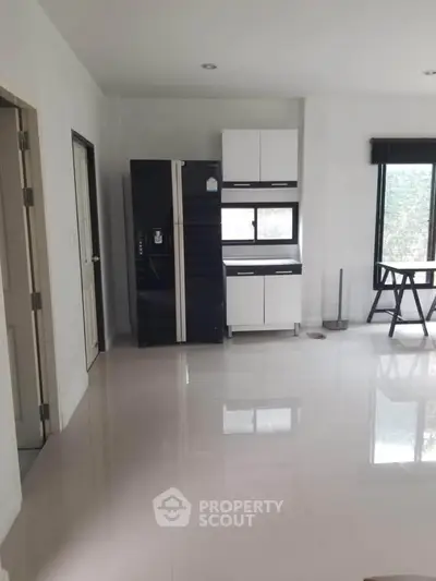 Spacious modern kitchen with sleek black fridge and ample natural light.
