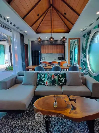 Luxurious open-plan living room with vaulted ceiling and modern kitchen in tropical villa.
