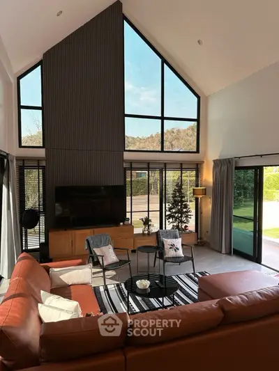 Spacious modern living room with high ceilings and large windows offering scenic views.
