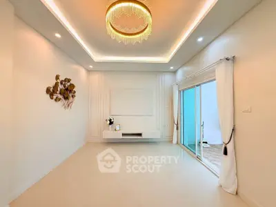 Elegant living room with chandelier and sliding glass doors leading to a balcony.