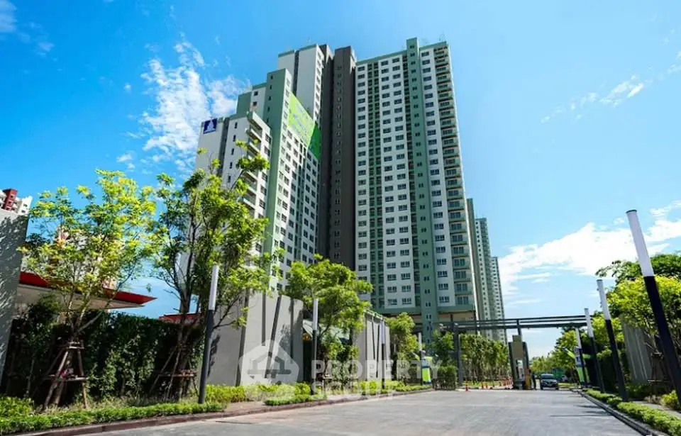 Modern high-rise building with lush greenery and clear blue sky, ideal urban living.