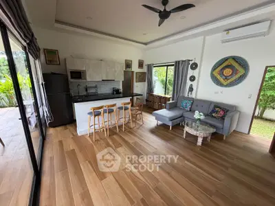 Spacious open-plan living room with modern kitchen and garden view, featuring stylish decor and ample natural light.
