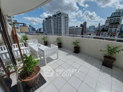 Spacious balcony with city skyline view and elegant outdoor seating.