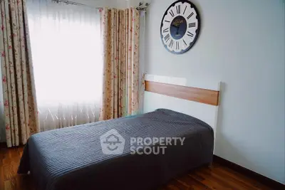 Cozy bedroom with single bed, floral curtains, and stylish wall clock.