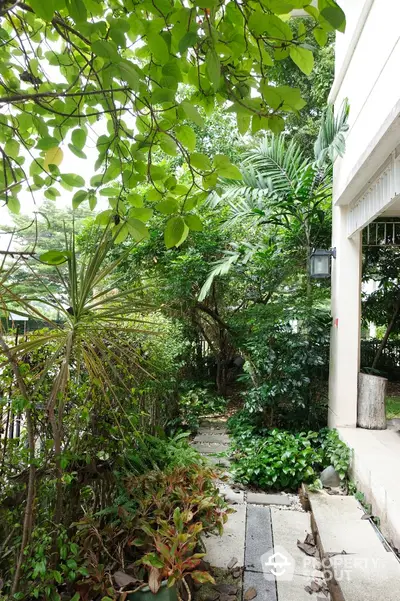 Lush garden pathway with tropical plants and greenery, offering a serene outdoor escape at a residential property.