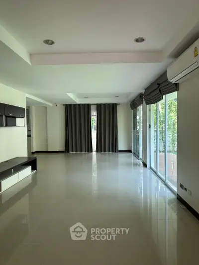 Spacious living room with large windows and modern design, perfect for natural light and comfort.
