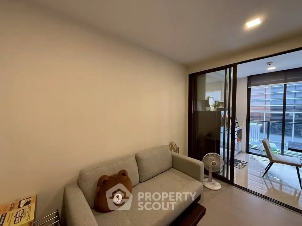 Cozy living room with modern decor and plush sofa, featuring a large window for natural light.