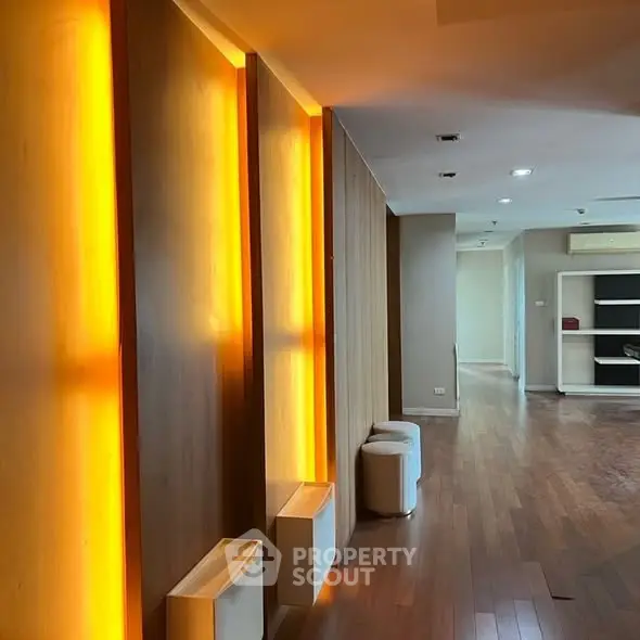 Modern interior with warm lighting and wooden flooring, showcasing a spacious and inviting living area.