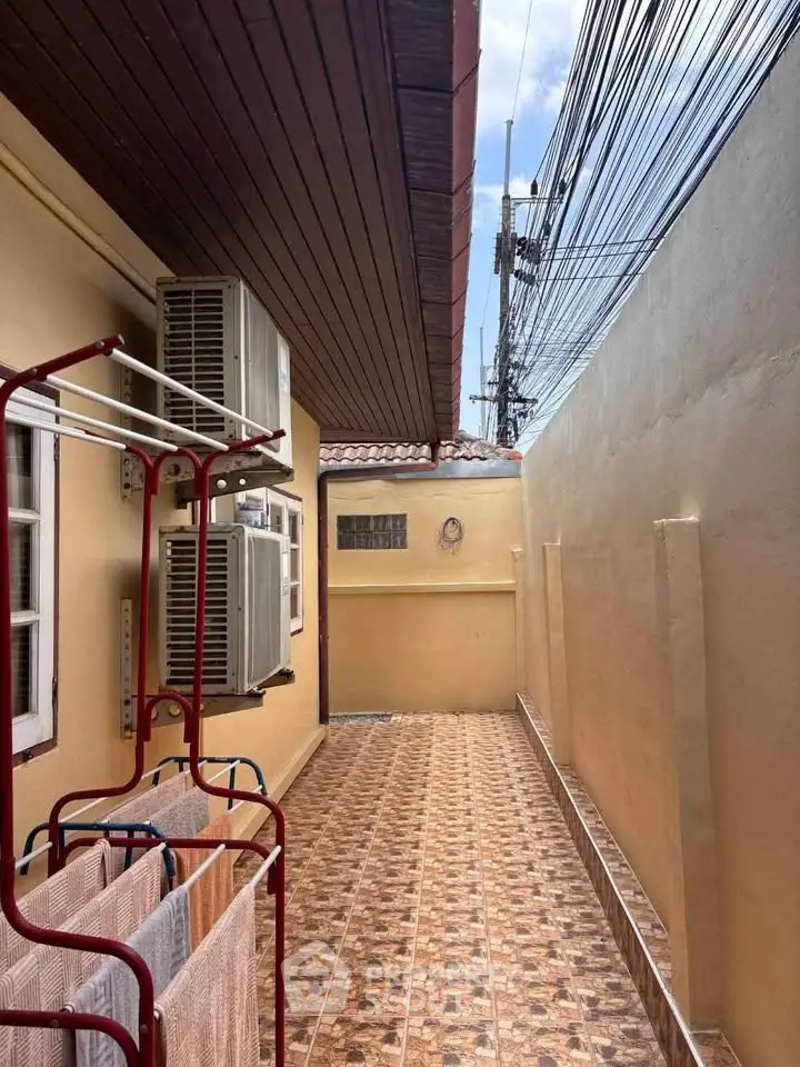 Charming outdoor corridor with tiled flooring and air conditioning units, perfect for utility space.