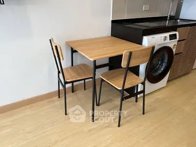 Modern kitchen with wooden dining set and washing machine, perfect for compact living spaces.