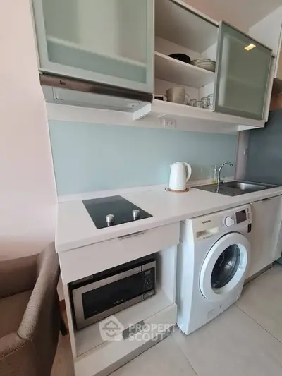 Modern kitchen with sleek appliances, washing machine, and microwave in compact layout.